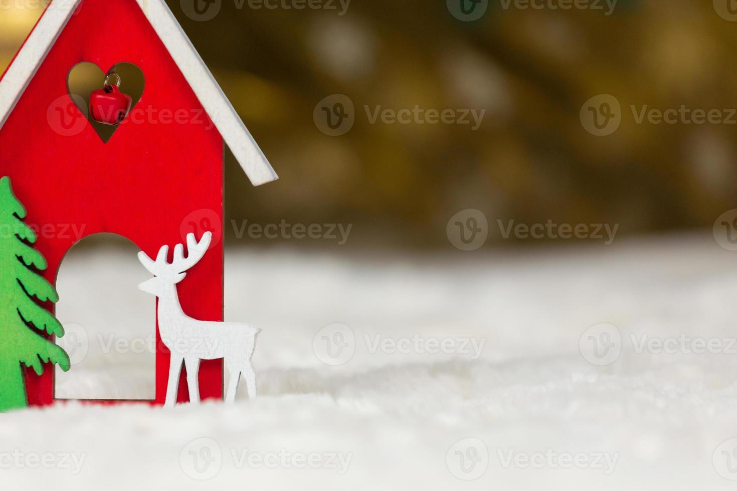 kerst houten speelgoed huis herten en boom op een witte deken die sneeuw imiteert foto