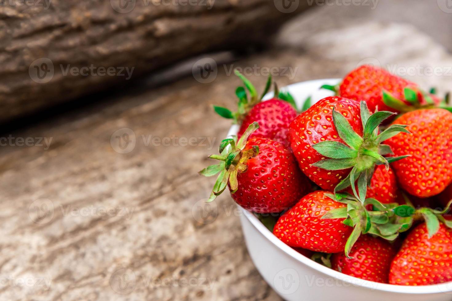 kom vol met verse aardbeien op bruine tafel foto