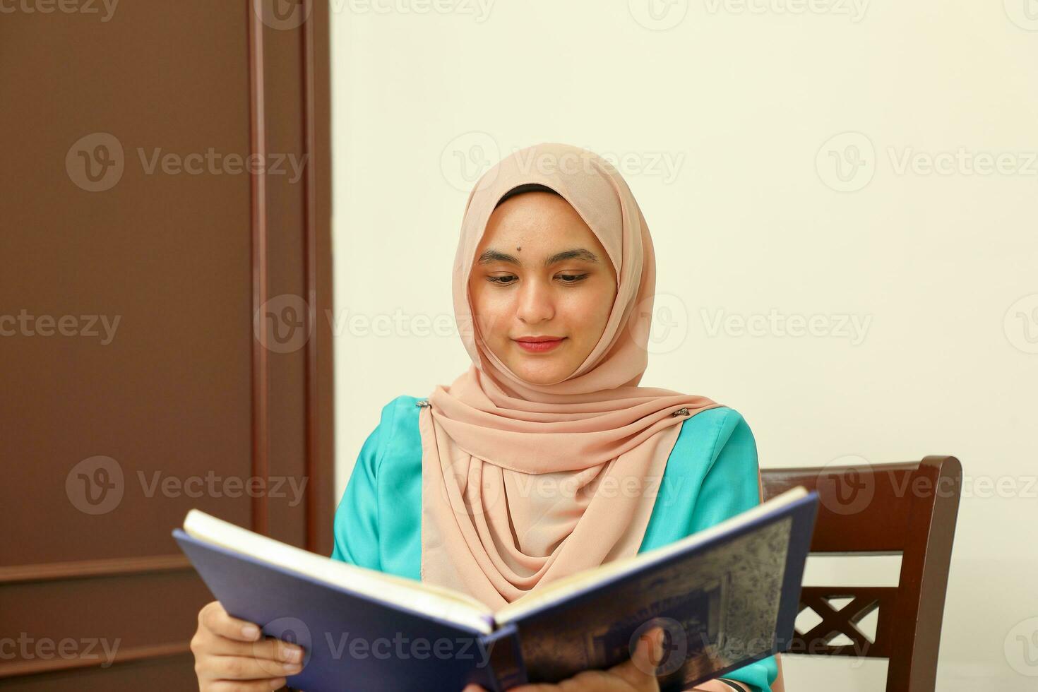 jong Aziatisch Maleis moslim vrouw vervelend hoofddoek Bij huis kantoor leerling zittend Bij tafel lezen boek document Notitie studie glimlach gelukkig kijken foto