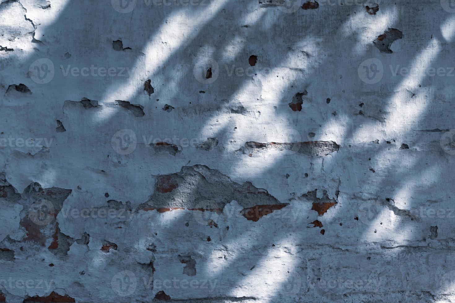 textuur van oude ruwe grunge verweerde muur met scheuren en lichte schaduw foto