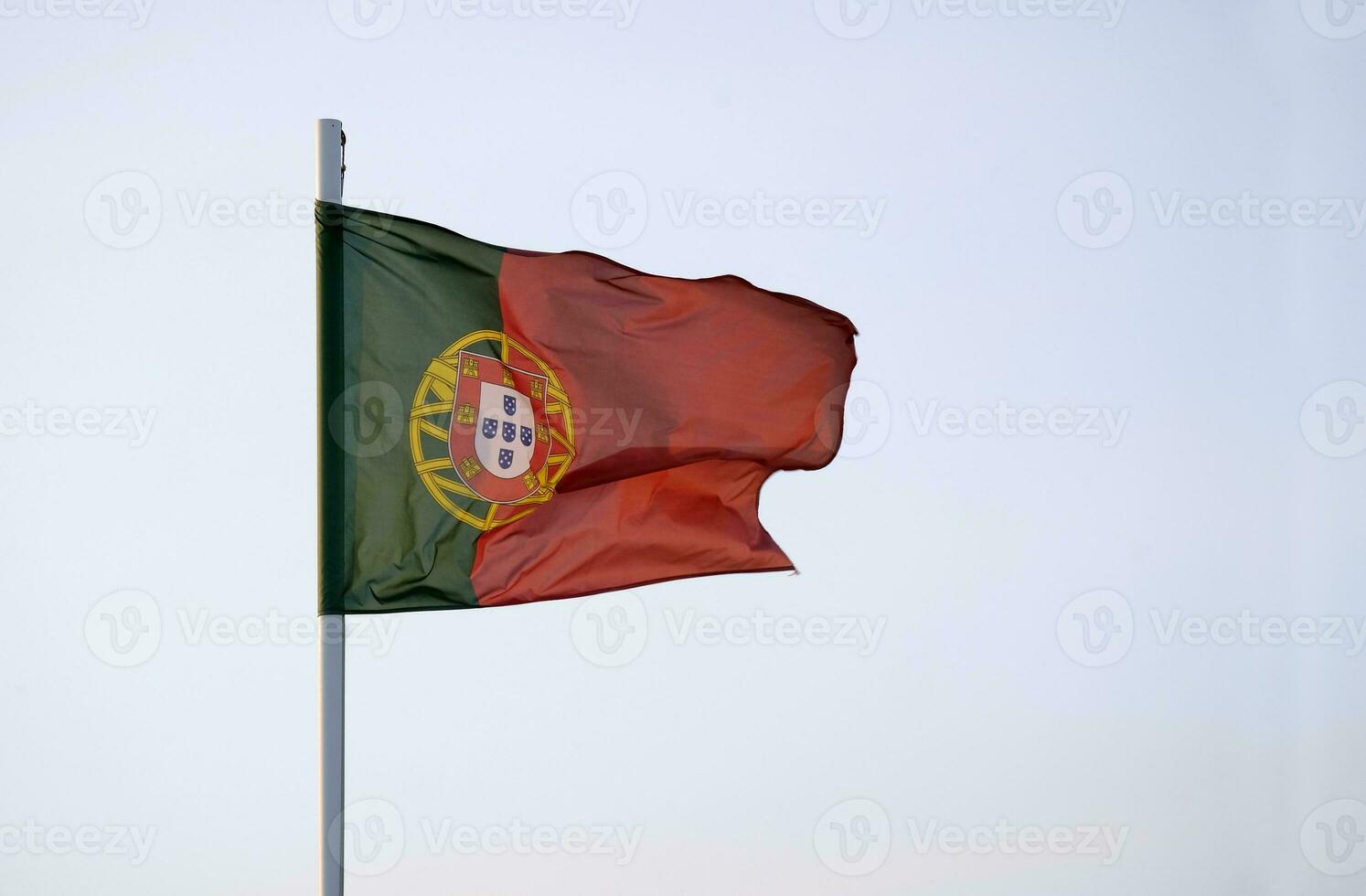 Portugees vlag golvend in de wind tegen een Doorzichtig lucht foto