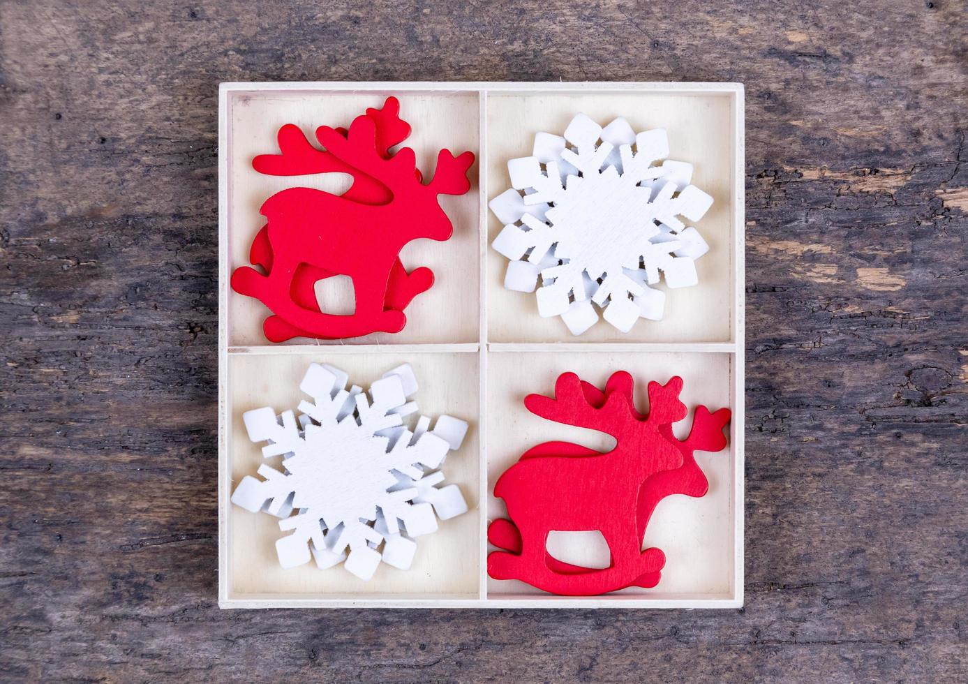 een witte doos met compartimenten op een houten achtergrond gevuld met rode kerst herten en sneeuwvlokken foto