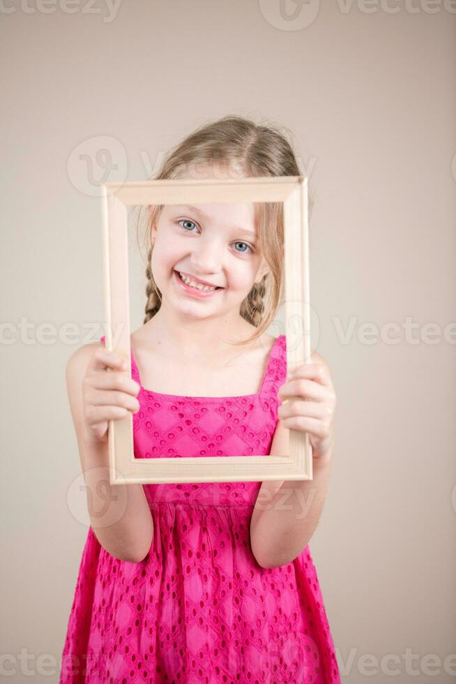 portret van een schattig weinig meisje Holding een afbeelding kader. studio schot foto