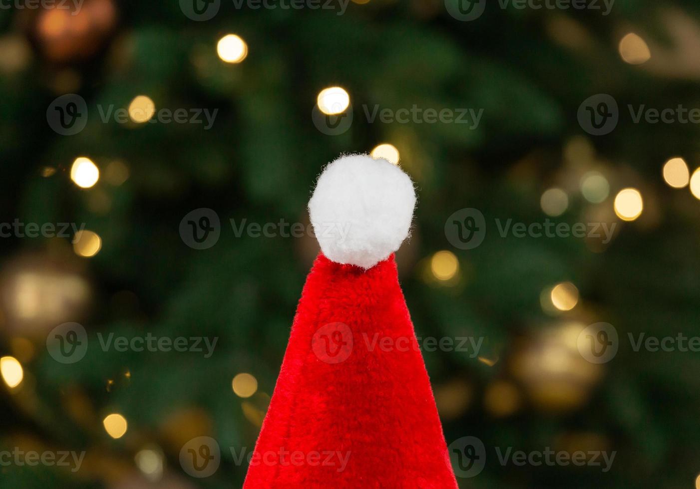 kerstmuts op de achtergrond van een kerstboom en slingers foto
