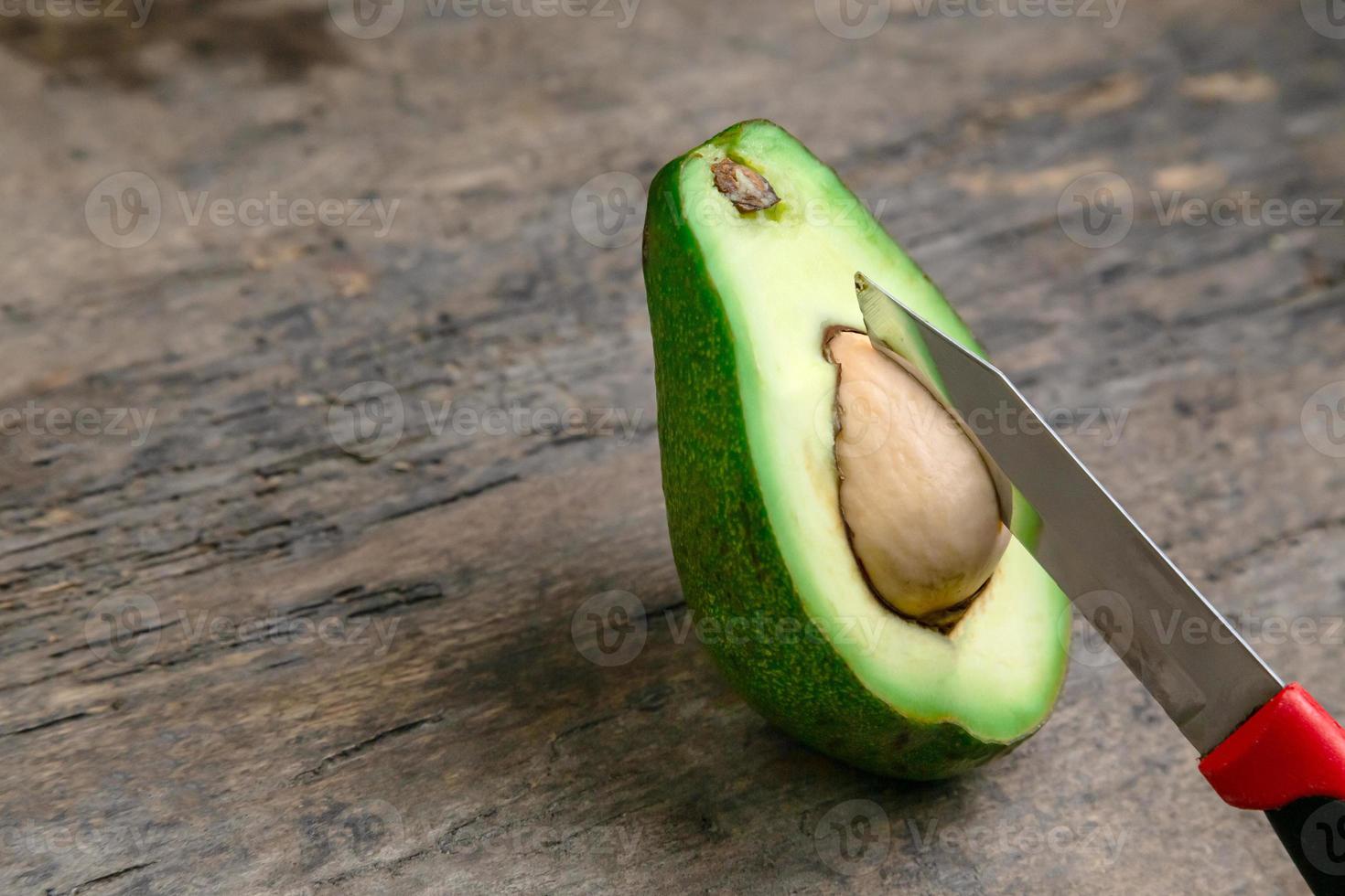 verse avocado in tweeën gesneden op een houten bord met mes achtergrond foto
