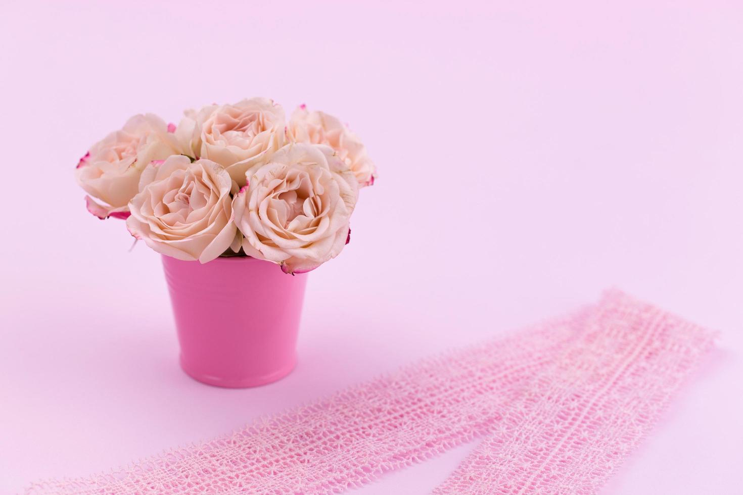 een boeket mooie rozen staat in een kleine emmer aan een kanten lint foto