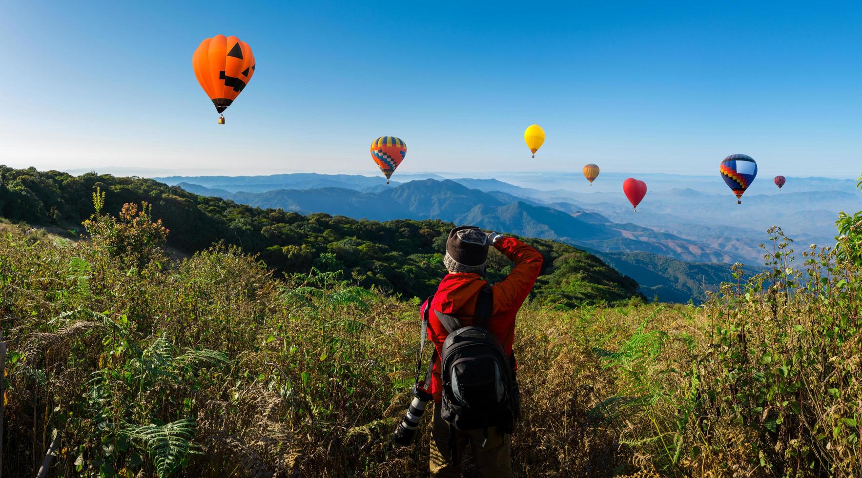 professionele fotograaf maakt landschapsfoto's op een berg met heteluchtballonnen op de achtergrond foto