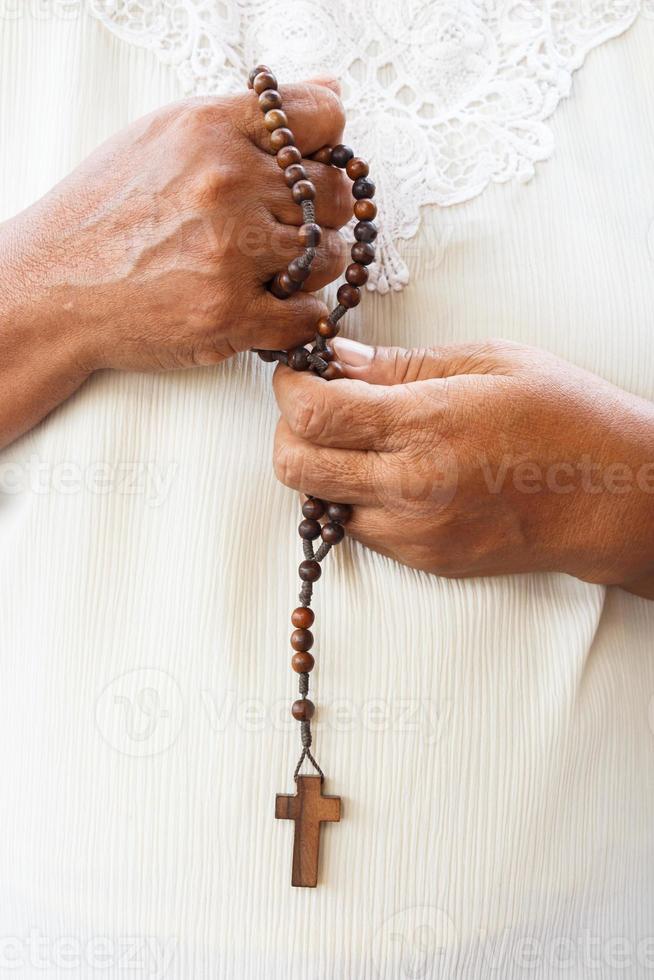 mens bidt tot god en houdt houten rozenkrans foto