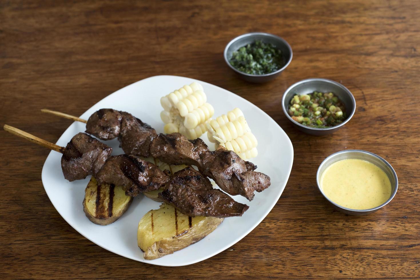 anticuchos Peruaanse keuken gegrilde spies rundvlees hart vlees met gekookte aardappel en witte maïs foto