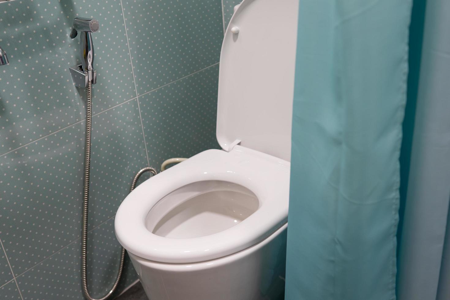 toilet doorspoelen keramische kom met groen gordijn in de badkamer foto