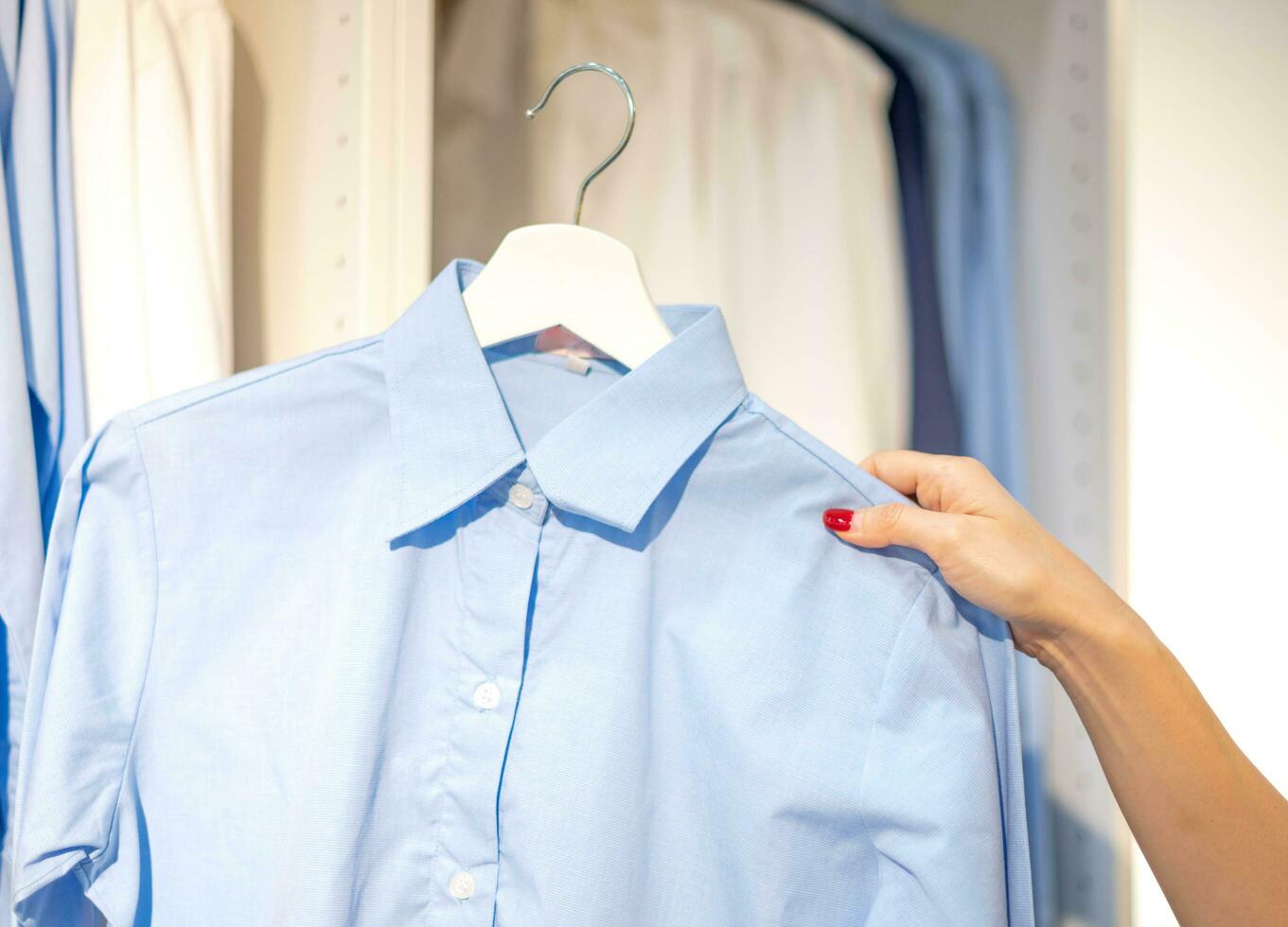 vrouw hand- kiezen kleren voor gecontroleerd patroon katoen kleur van de t-shirt en vergelijken kwaliteit Aan de rek in kleding winkel Bij afdeling op te slaan. foto