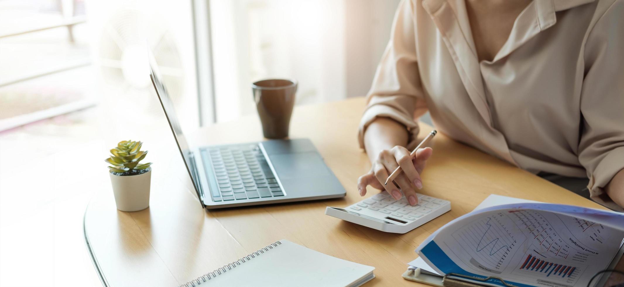 zakenvrouw werken in financiën en boekhouding analyseren financiële begroting met rekenmachine en laptop op kantoor foto