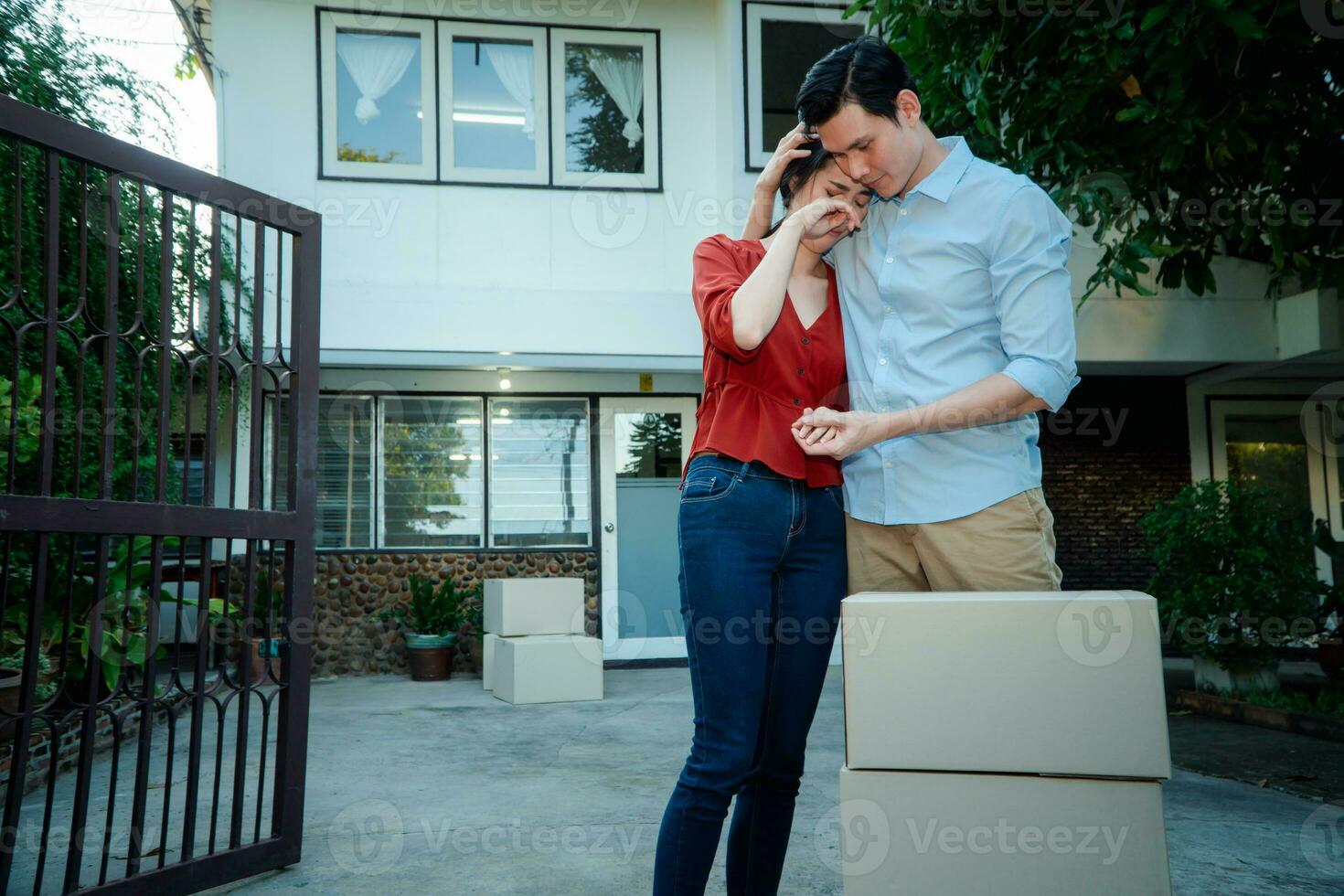 Mens geruststellend zijn vrouw en vrouw knuffelen haar man en huilen in voorkant van de huis en vol van karton dozen gedurende de vervoer in Actie uit dag, in beweging huis concept foto