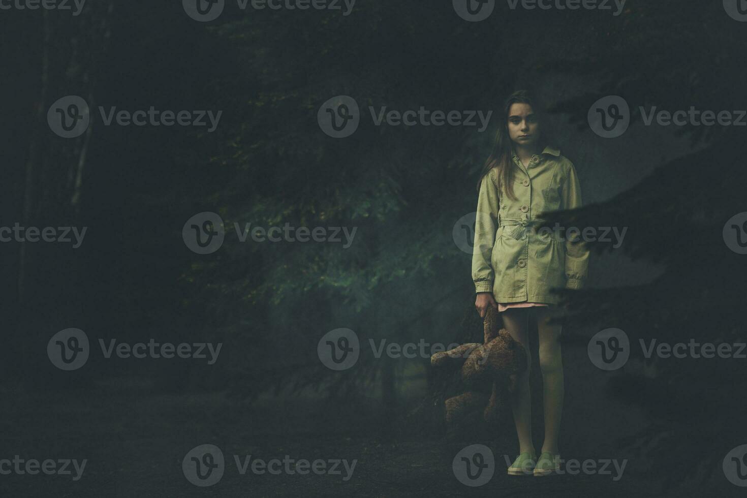 verloren emotieloos meisje met teddy beer in de midden- van donker nacht Woud foto