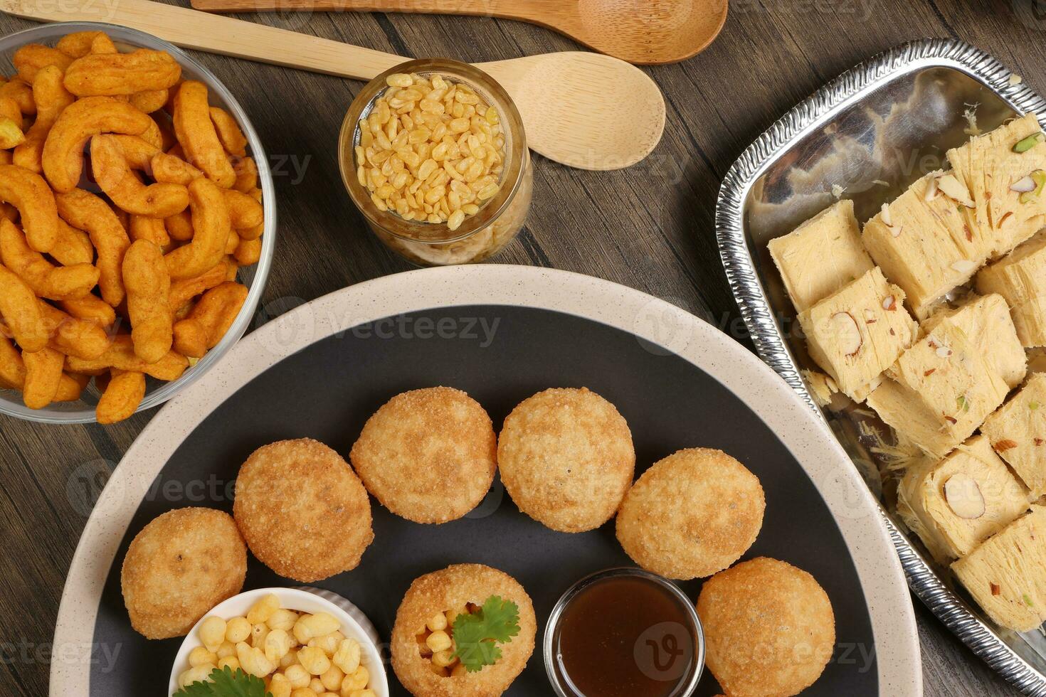 waarheid van Indisch Bengaals straat voedsel thee tijd snacks ui pakoda knapperig pittig linzen moong dal bakken zoet shompapri chaat pani puri fuska Aan rustiek retro tafel bord messing koper potten zilver dienblad foto