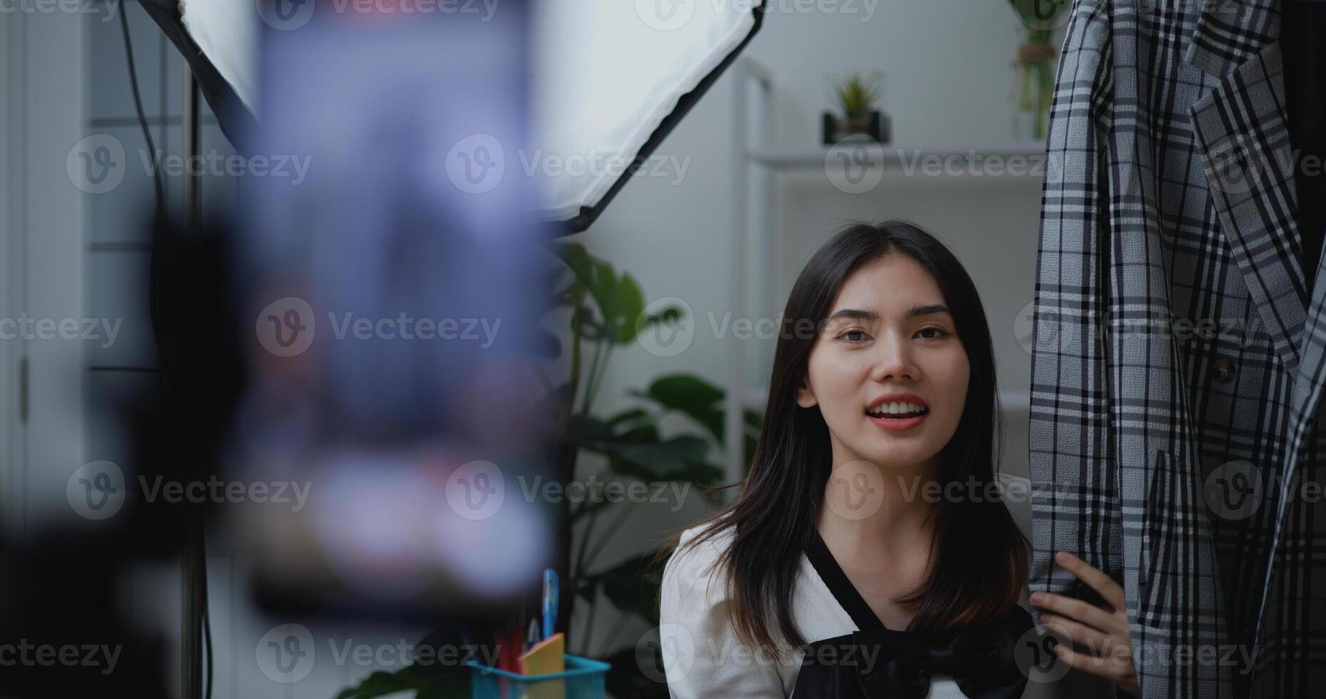 jong Aziatisch vrouw mode ontwerper gebruik makend van mobiel telefoon leven stomen foto