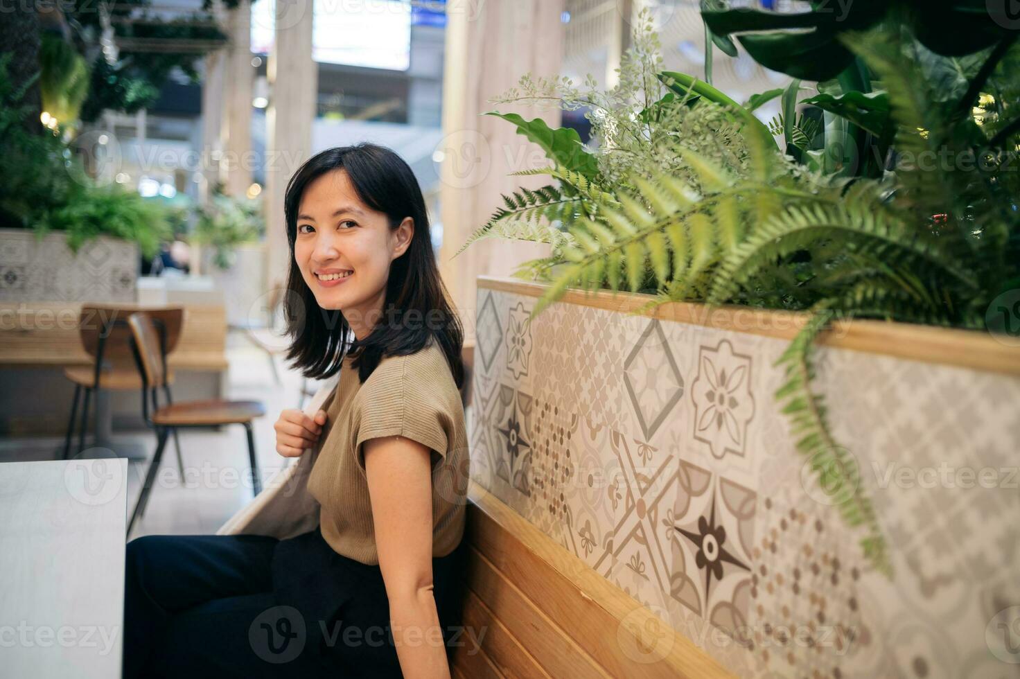 glimlachen mooi Aziatisch vrouw zittend in cafetaria Bij boodschappen doen winkelcentrum. foto