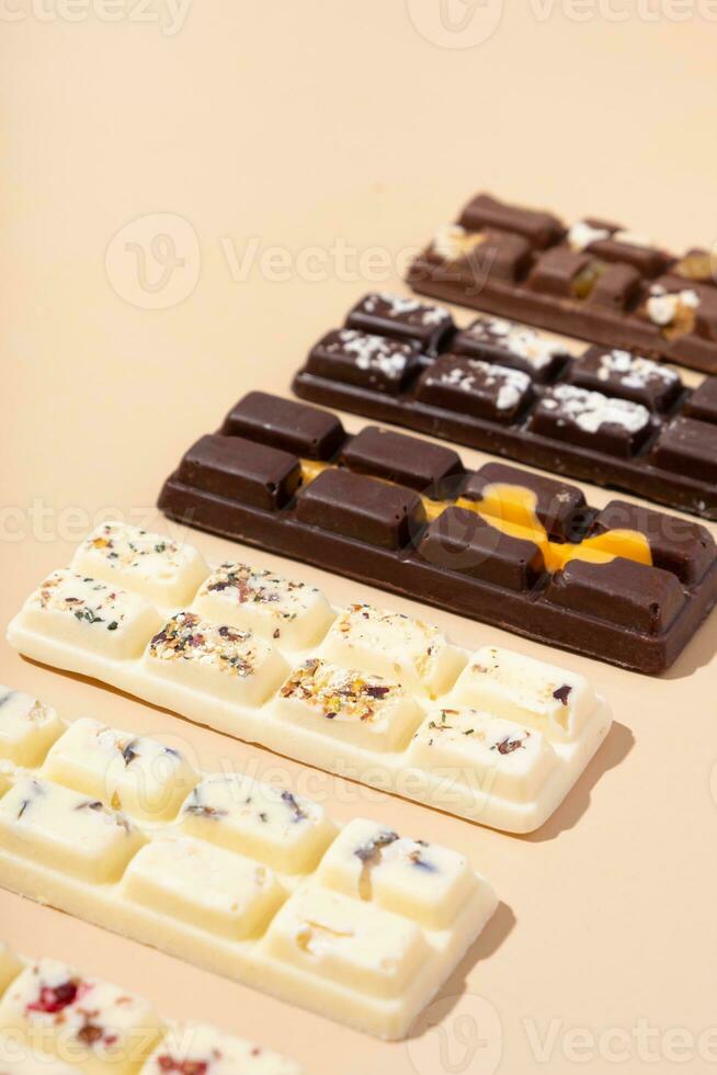 ambacht wit, melk en zwart chocola snoepjes Aan beige achtergrond vlak leggen, top visie foto