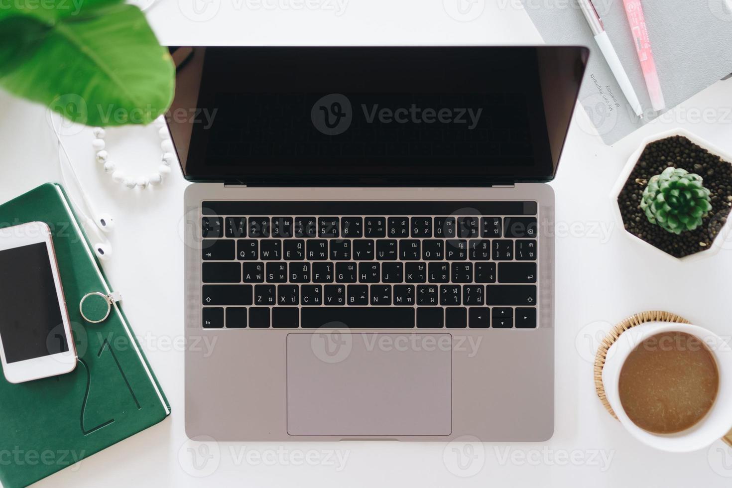 bovenaanzicht van moderne laptop of notebook met telefoon om bureaudesktop op tafel te werken foto