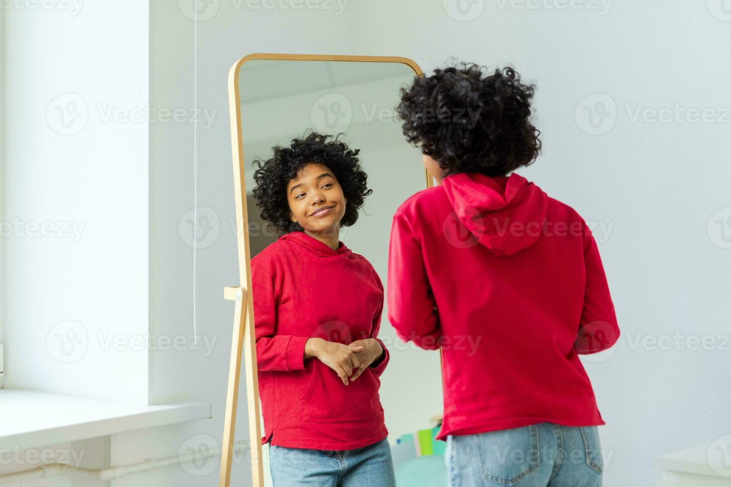 liefde jezelf. mooi jong glimlachen Afrikaanse Amerikaans vrouw dansen genieten van haar spiegel reflectie. zwart dame op zoek Bij spiegel op zoek zelfverzekerd en gelukkig. zelf liefde concept. foto