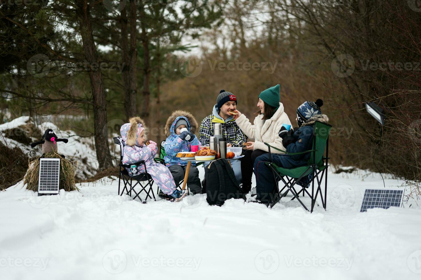 familie met drie kinderen in winter Woud uitgeven tijd samen Aan een picknick. foto