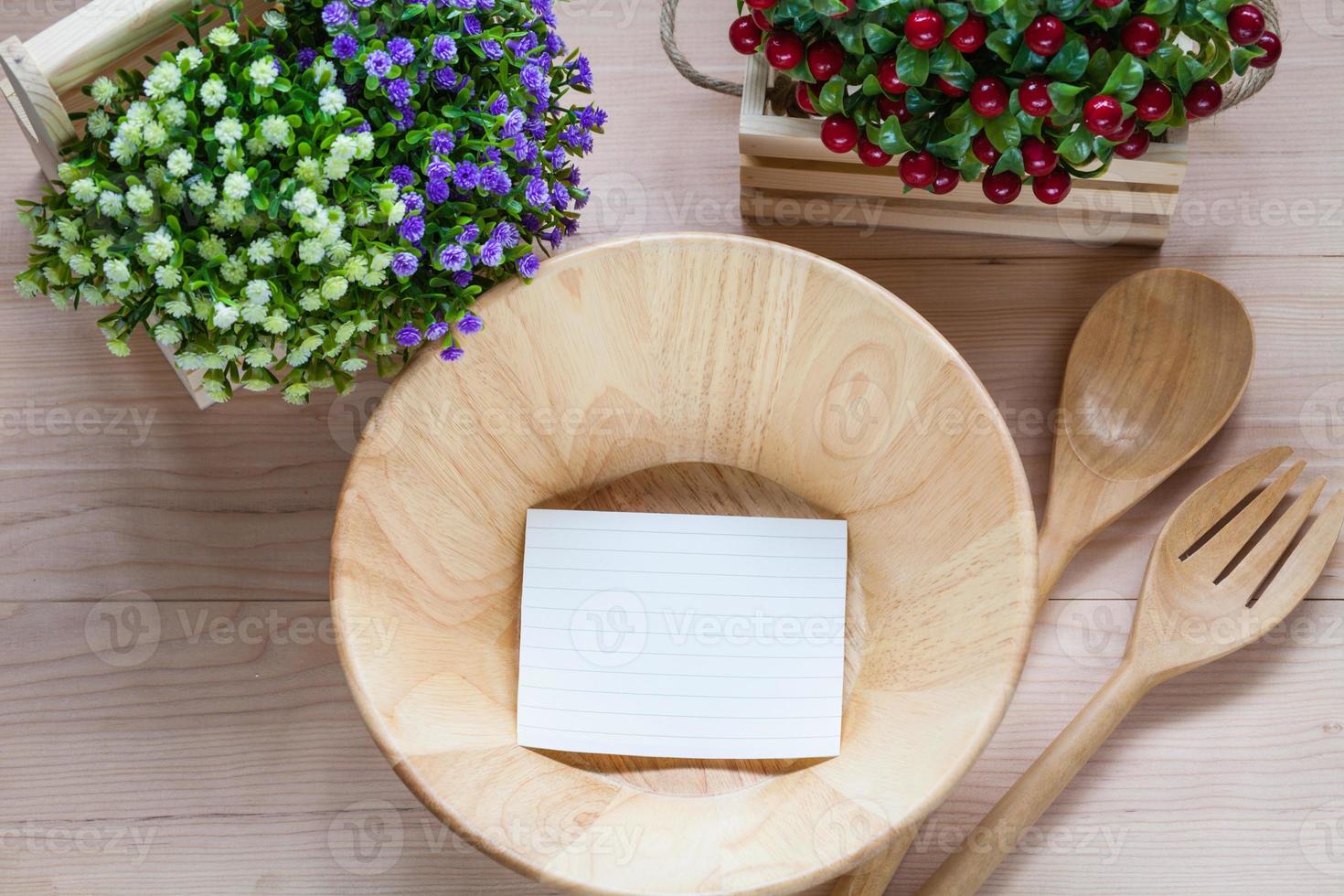 houten kom met lepel-vork en aantekeningen op papier op houten achtergrond foto