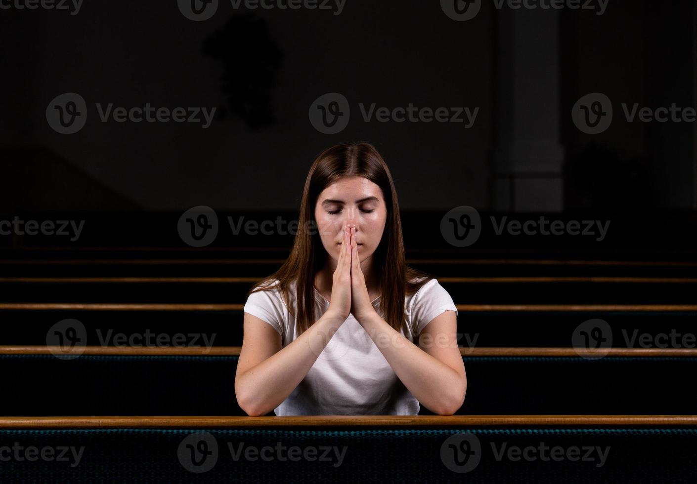 een christelijk meisje in een wit overhemd bidt met nederig hart in de kerk foto