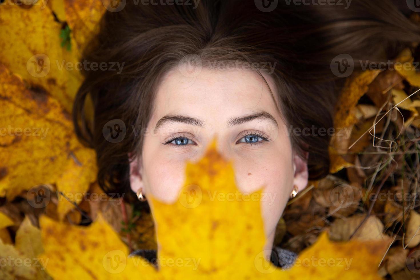 bovenaanzicht van een schattig meisje met blauwe ogen met een mooi geel esdoornblad foto