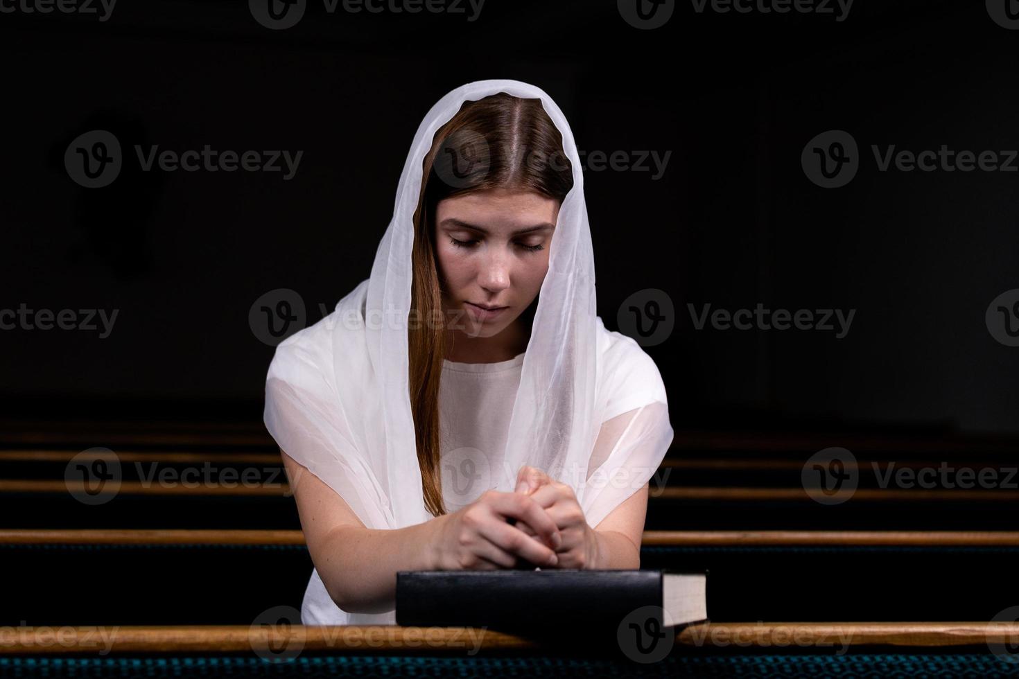 een christelijk meisje dat met nederig hart bidt in de kerk foto