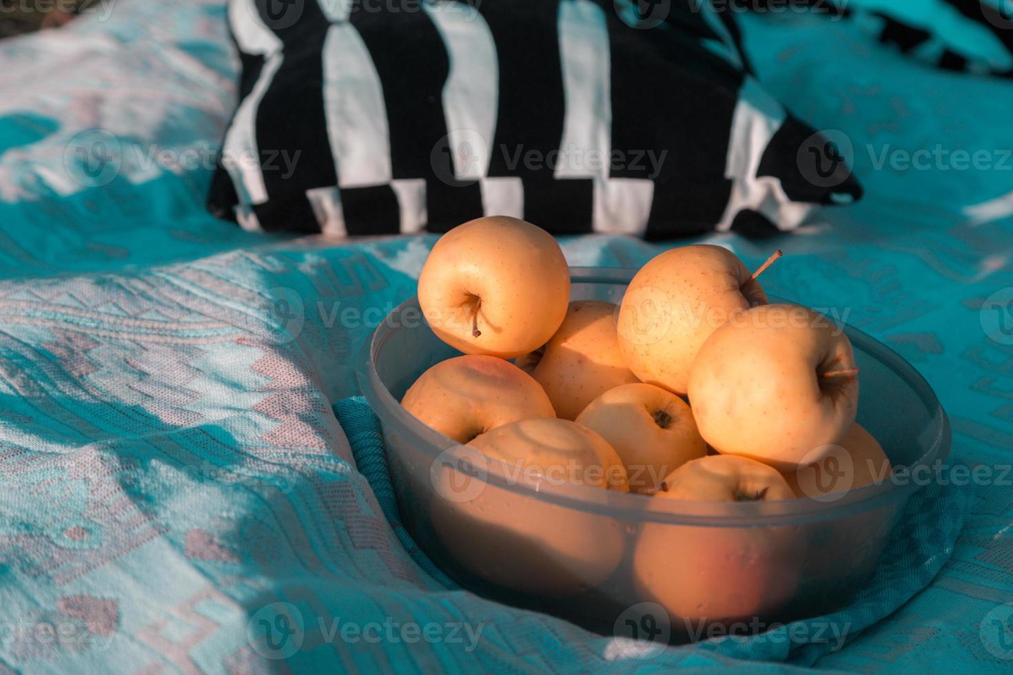 plaat met gele appels op een blauwe sprei op een zonnige dagpicknick foto