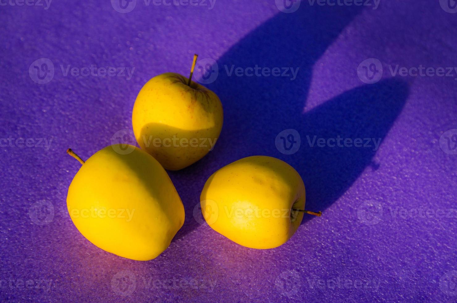 gele appels op paarse achtergrond foto