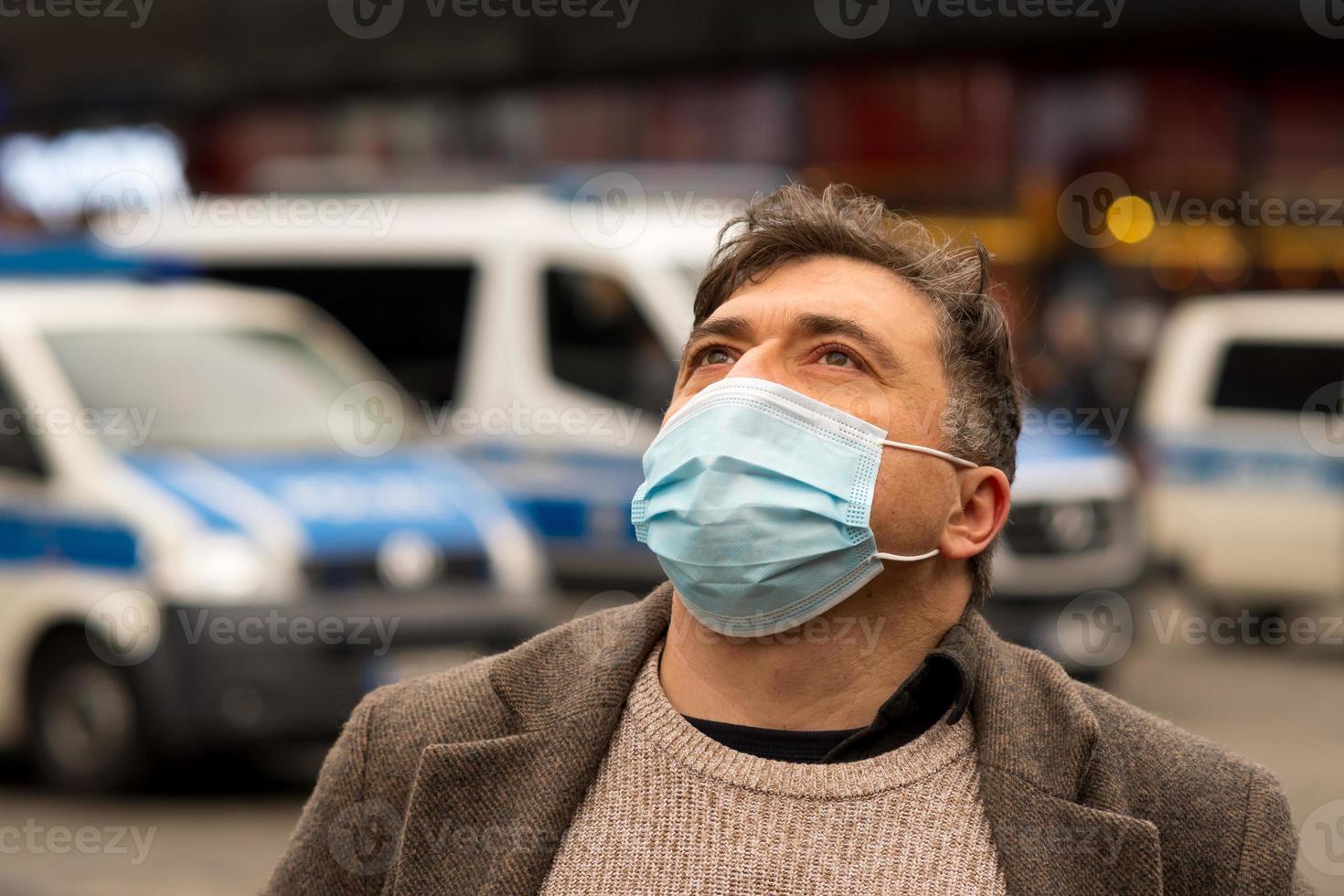 openluchtportret van een man die zijn gezicht beschermt met een medisch of chirurgisch masker dat naar boven kijkt foto