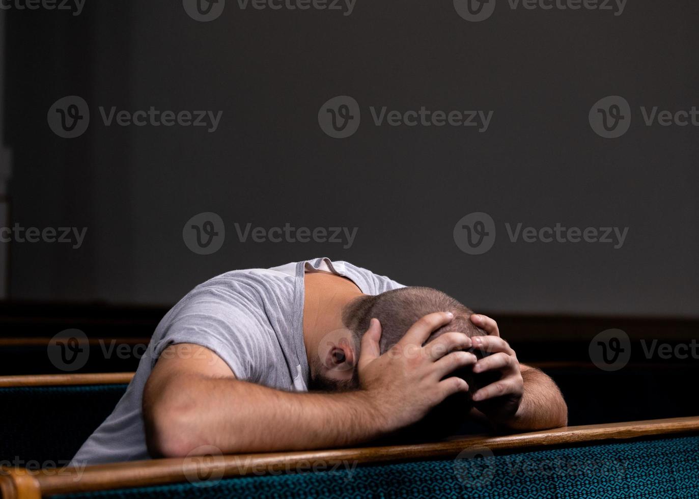 een trieste christelijke man in wit overhemd zit met nederig hart in de kerk te bidden foto