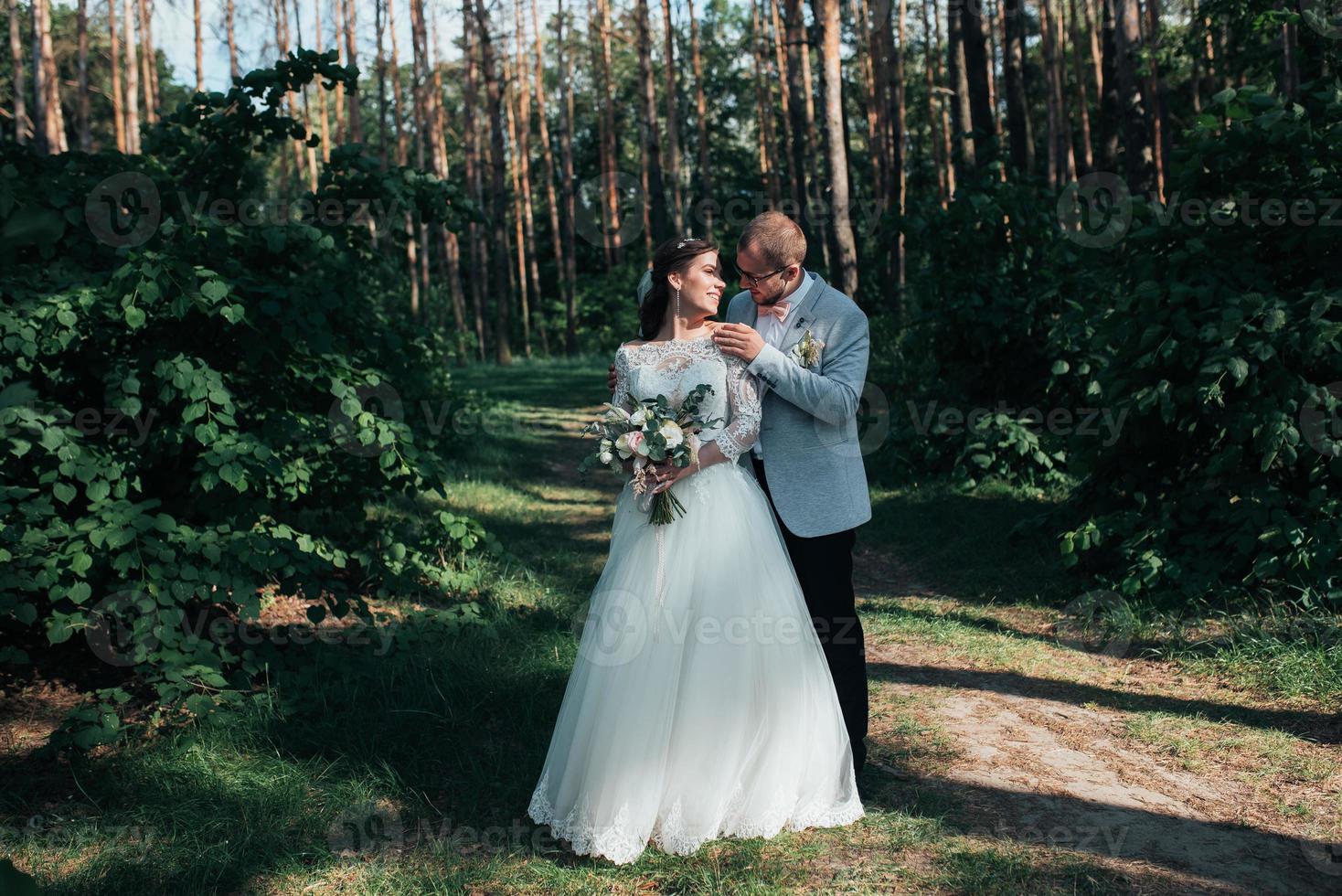 trouwfoto van de bruid en bruidegom in een grijsroze kleur op de natuur in het bos en de rotsen foto