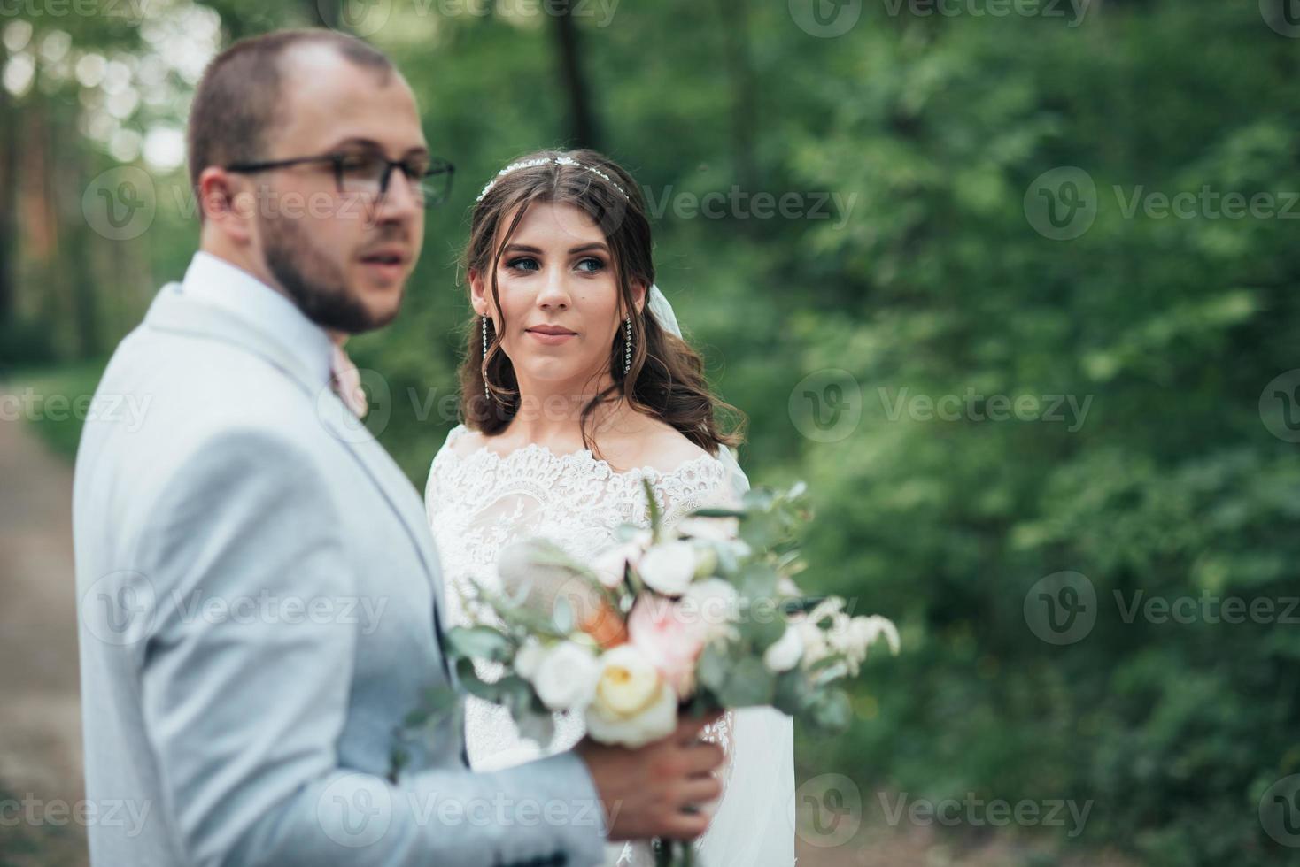 trouwfoto van de bruid en bruidegom in een grijsroze kleur op de natuur in het bos en de rotsen foto