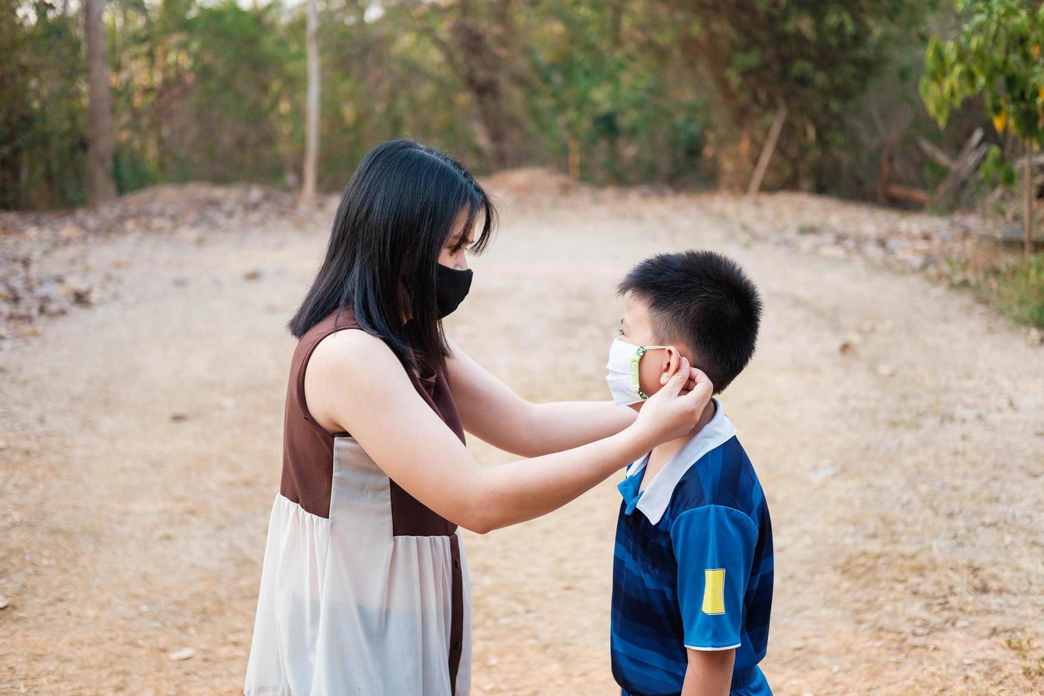 de moeder draagt een masker om haar zoon te beschermen tegen het covid19-virus foto