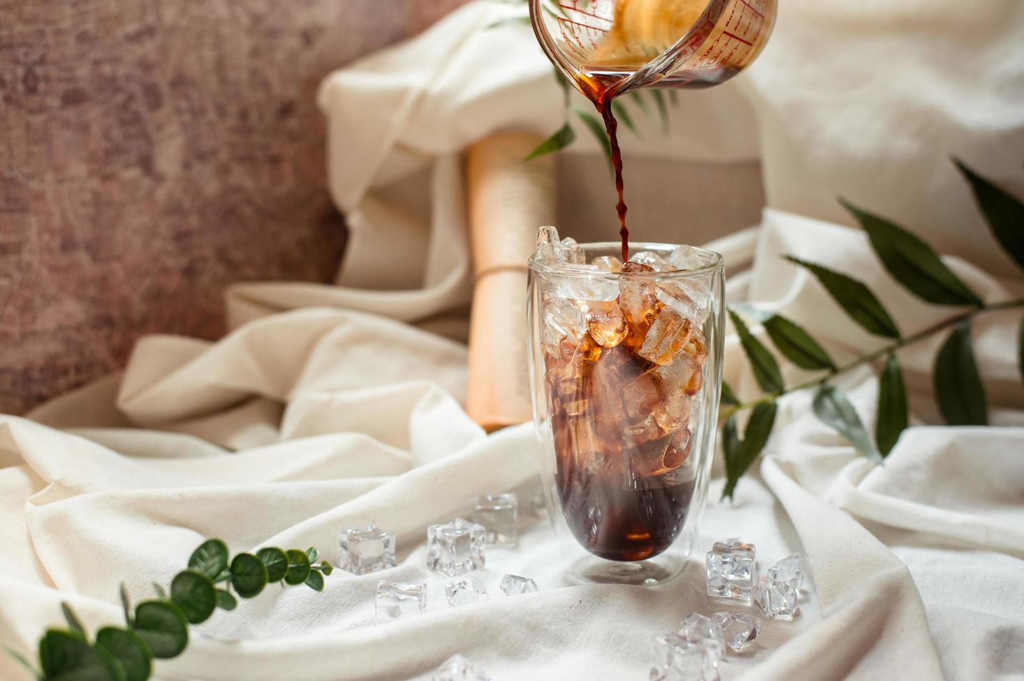 barista melk gieten in een glas ijskoffie foto