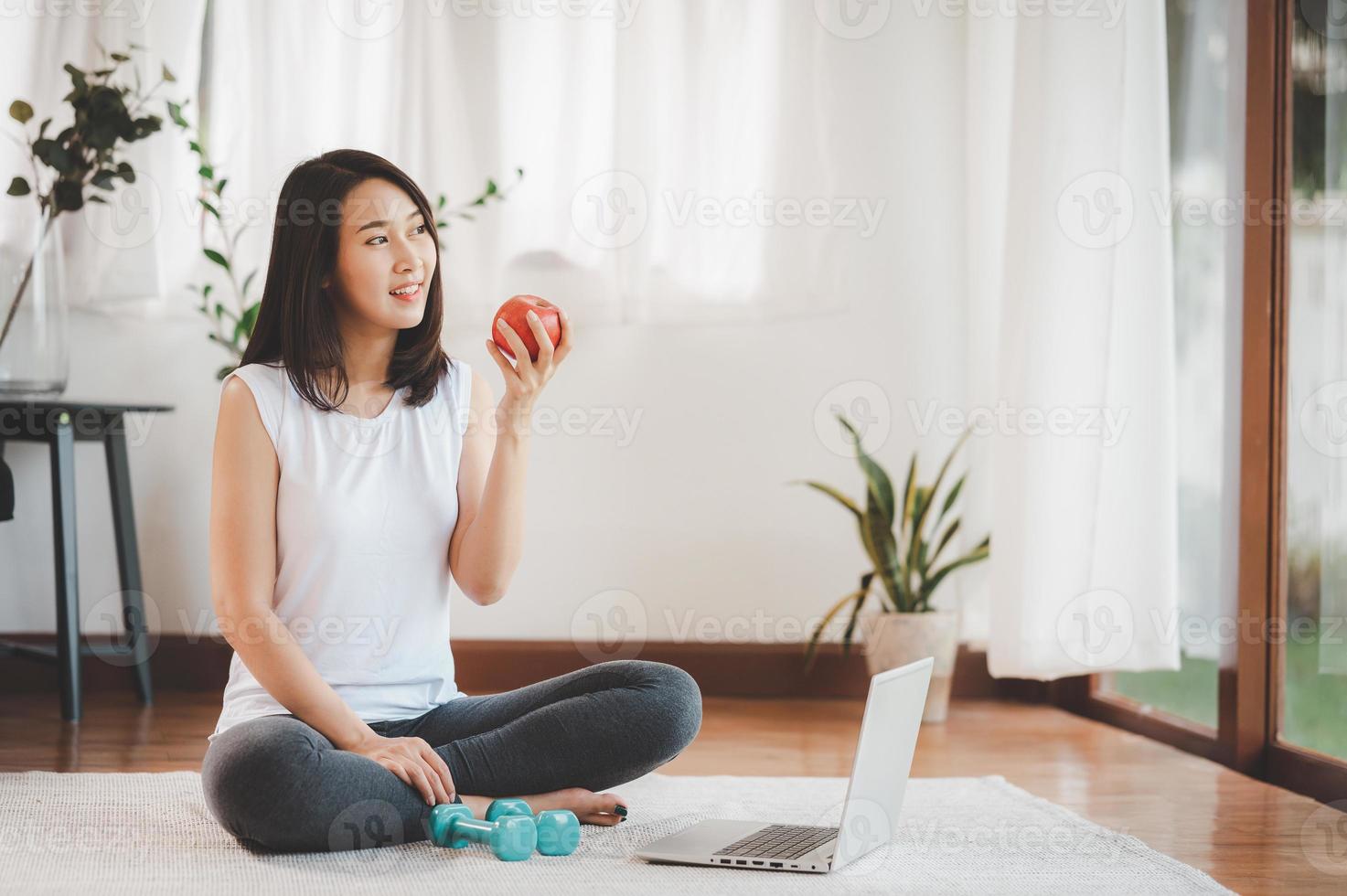 vrouw die appel eet alvorens online oefenklas van laptop te doen foto