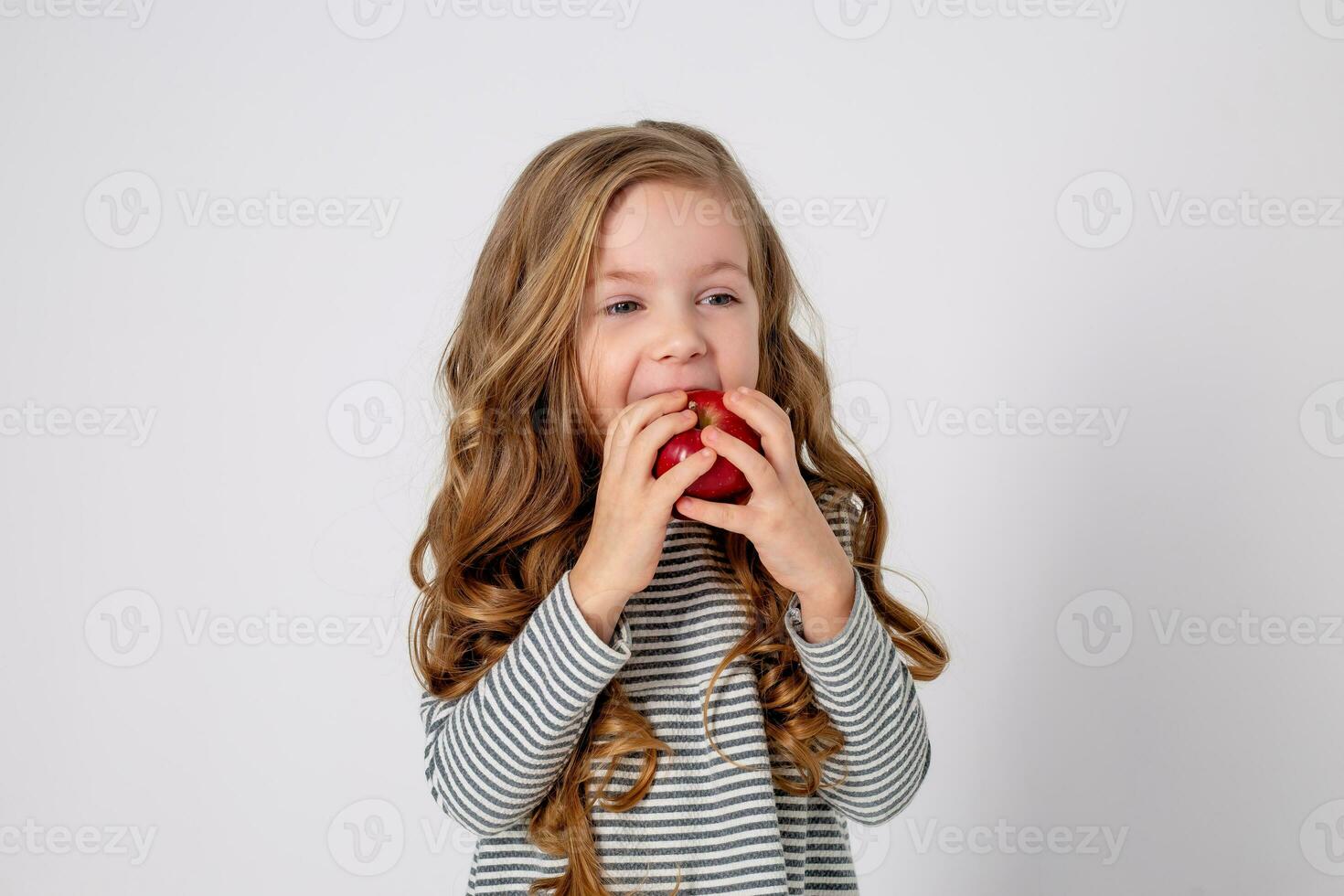 portret van een klein gelukkig meisje van Slavisch uiterlijk aan het eten een rood appel. plaats voor tekst foto