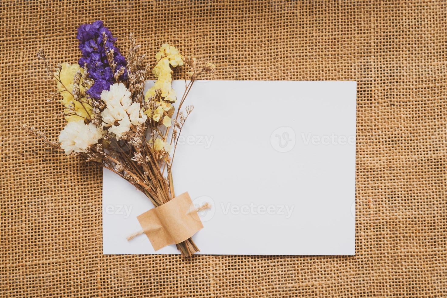 een witte kaart versierd met een bos veelkleurige droge bloemen op de bruine stof foto
