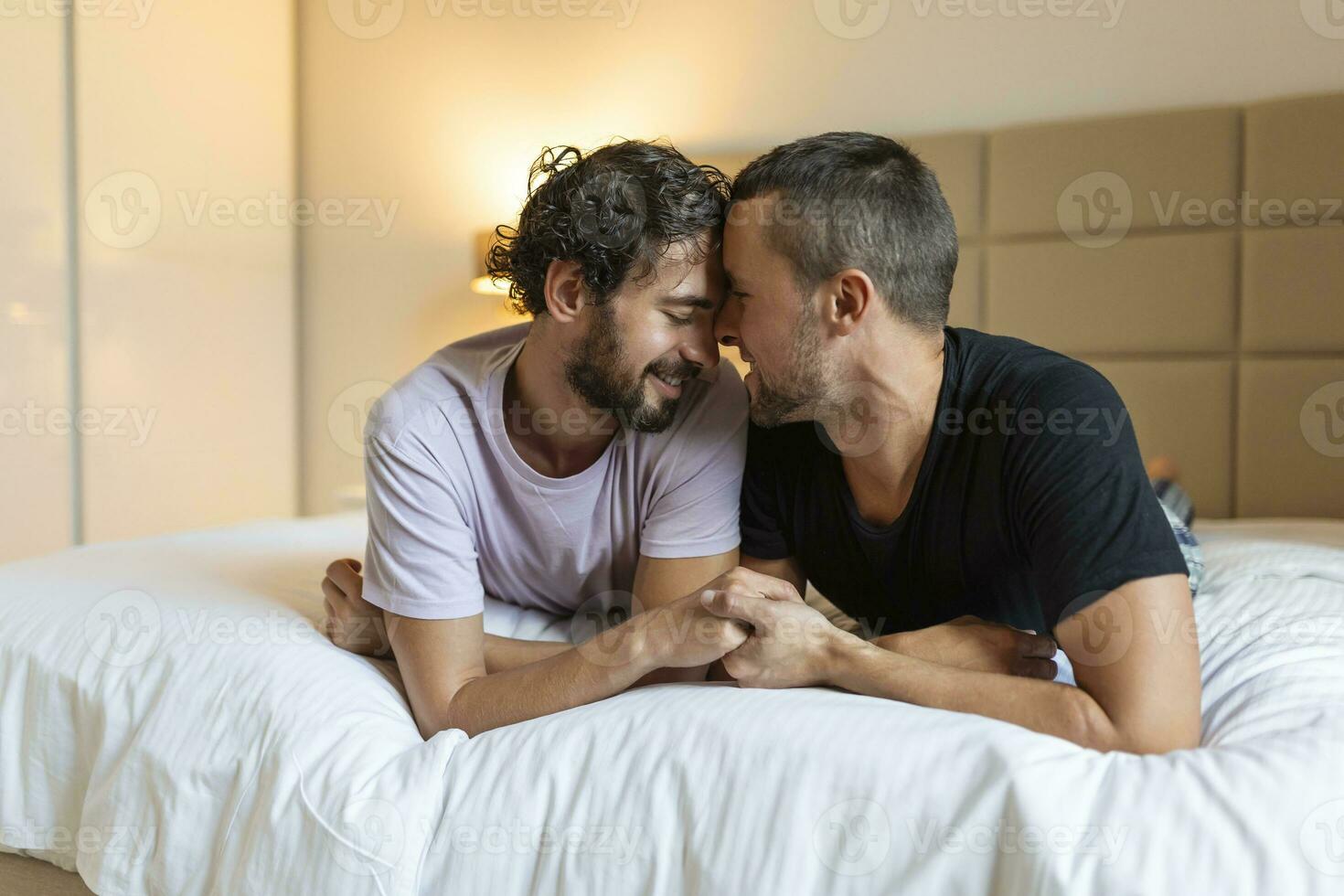 gelukkig homo paar aan het liegen naar beneden Aan de bed Bij huis, knuffelen en flirten. lgbt homo paar liefde momenten geluk concept foto