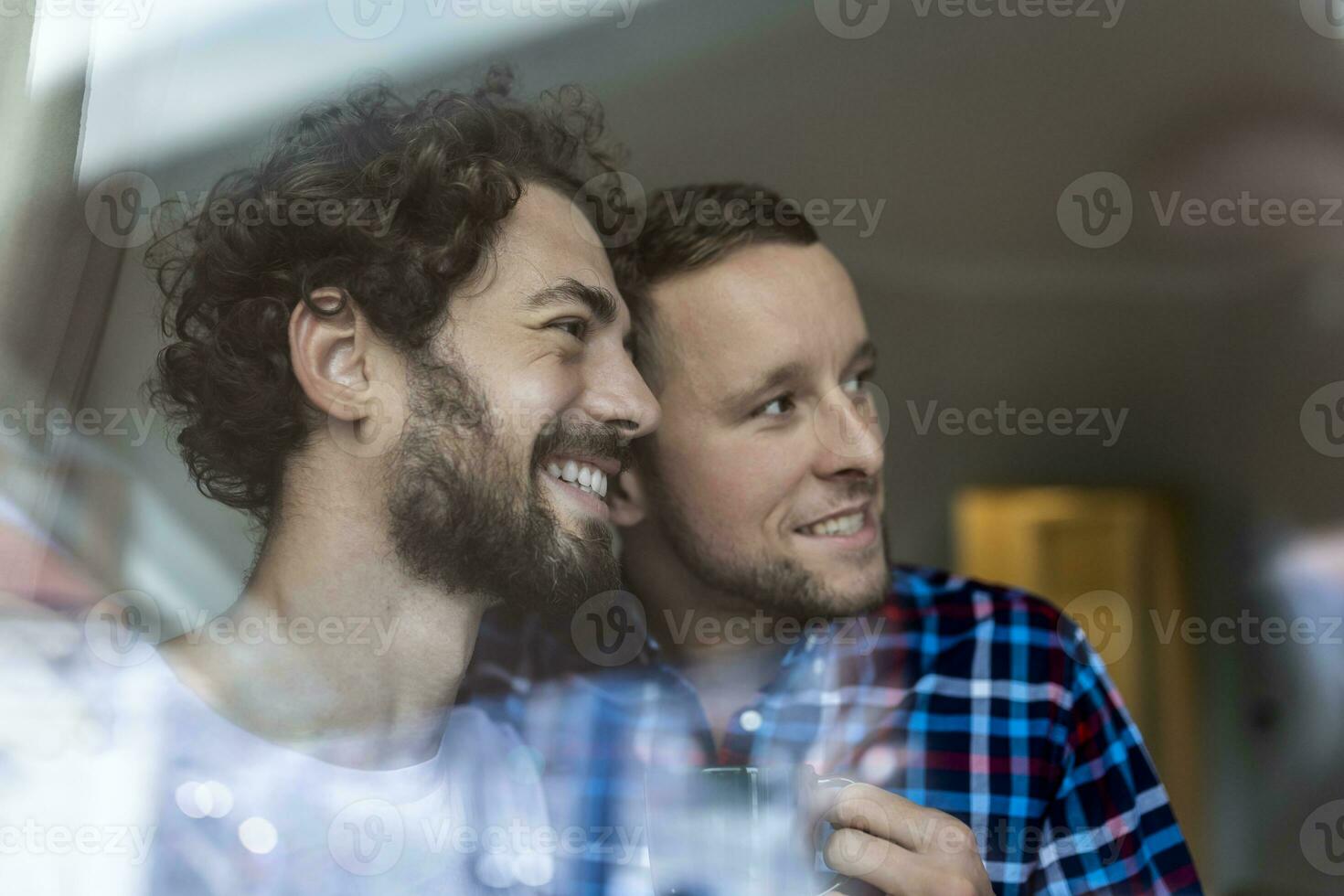 jong homo paar in liefde op zoek uit de venster. twee jong androgyn mannen glimlachen samen en hebben koffie. foto