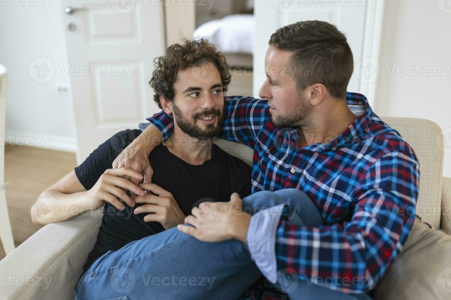 liefhebbend dezelfde seks mannetje homo paar aan het liegen Aan sofa Bij huis en ontspannend, knuffelen samen foto
