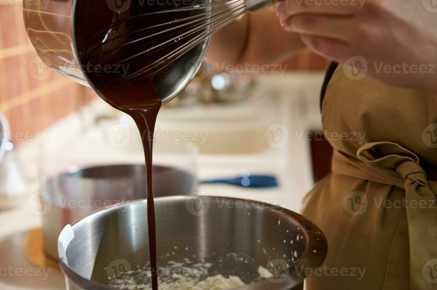 bijgesneden visie gebakje chef gebruik makend van garde, toevoegen gesmolten banketbakkerij donker chocola in een kom van voedsel bewerker foto