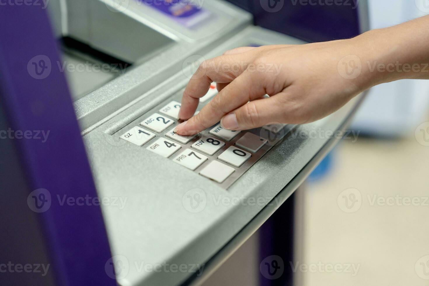 vrouw hand- drukken Purper Geldautomaat machine in een boodschappen doen winkelcentrum foto