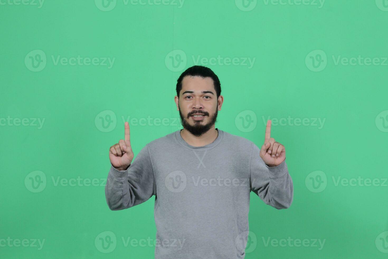 gebaard Aziatisch Mens poses vervelend een grijs overhemd tegen een groen achtergrond foto