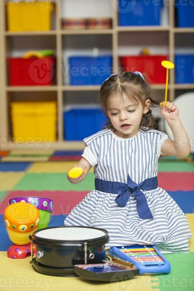 zoet weinig meisje aan het leren naar Speel instrumenten. foto