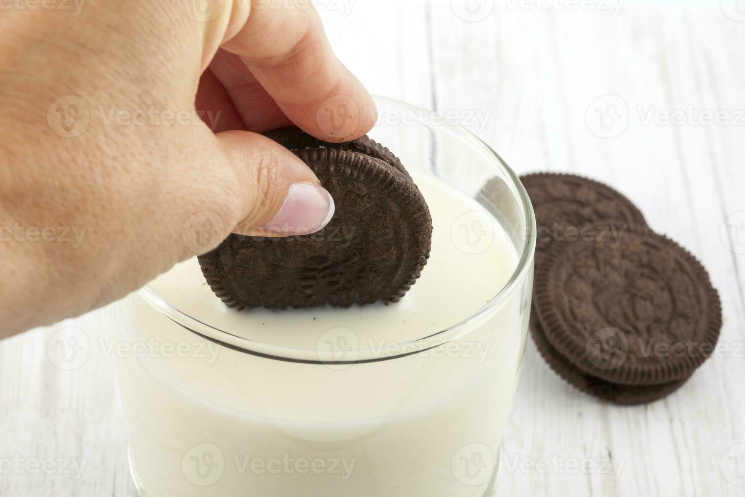 dichtbij omhoog van een vrouw dompelen chocola koekjes in melk foto