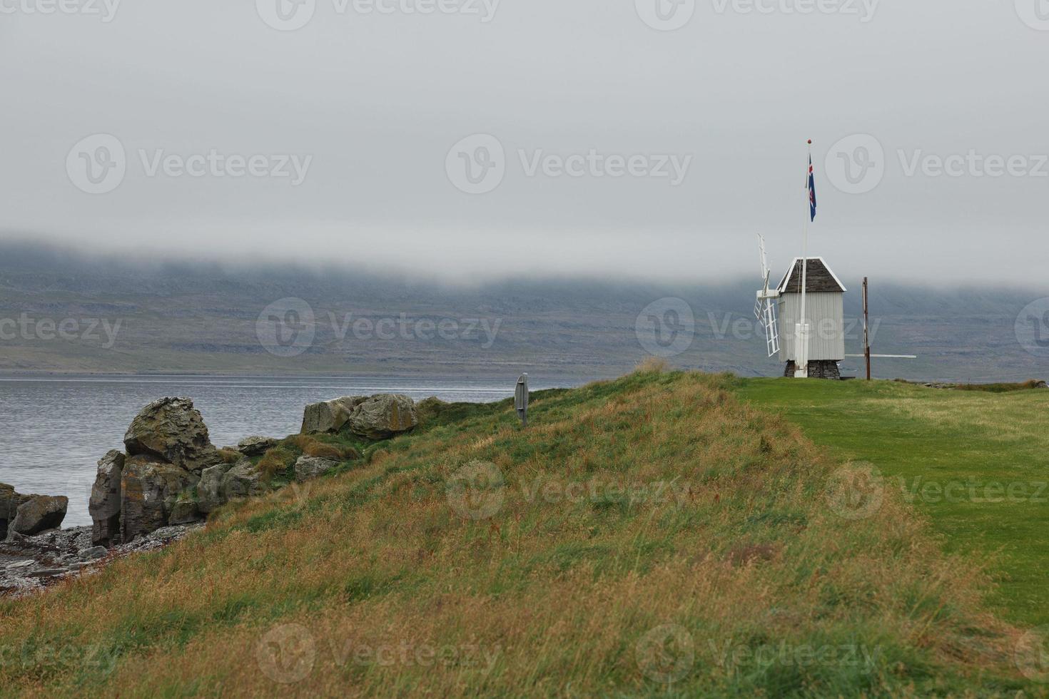windmolen en IJslandse vlag in Vigur-eiland in een bewolkte en winderige dag IJsland foto