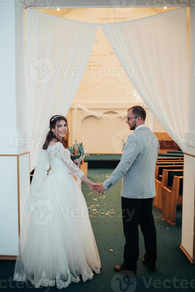 jonge bruid en bruidegom op hun trouwdag in een kerkgebouw foto